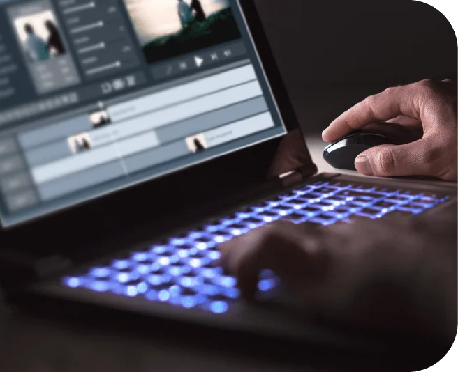 Hands using a laptop with a video editing timeline on screen.