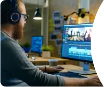 Person wearing headphones editing video at a workstation.